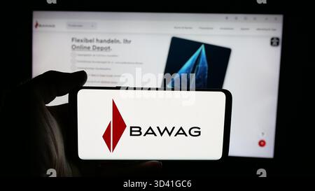 In dieser Fotoabbildung hält eine Person ein Handy mit dem Logo des österreichischen Finanzdienstleistungsunternehmens BAWAG auf dem Bildschirm vor der Webseite. Stockfoto