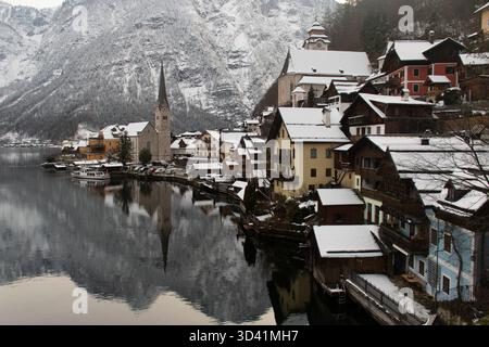Klassischer Winterpanorama auf Hallstatt mit Kirchturm und schneebedeckten Häusern am See. Stockfoto