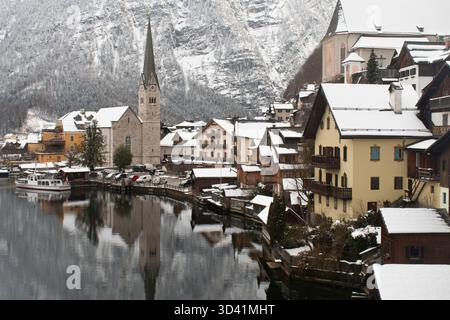Klassischer Winterpanorama auf Hallstatt mit Kirchturm und schneebedeckten Häusern am See. Stockfoto