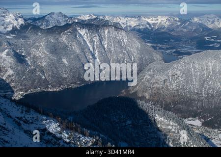 Winterpanorama über dem Hallstätter See mit steilen, verschneiten Klippen und weit entfernten Bergketten. Stockfoto