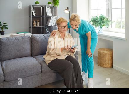 Hilfe von der Pflegekraft bis zur Seniorin bei der Nutzung des Mobiltelefons, Unterstützung von der Krankenschwester für alte Patienten Stockfoto