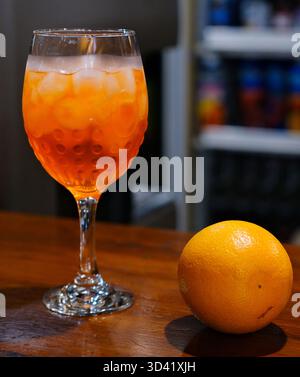 Glas klassischer roter Cocktail mit Eis- und Orangenscheiben auf grünem Gartenhintergrund. Hochwertige 4K-Aufnahmen Stockfoto