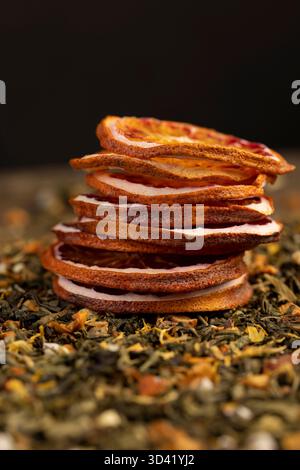Hochwertiger grüner Tee mit zusätzlichen Aromen und Fruchtstücken und geschnittenen getrockneten roten Orangen, hellen großen trockenen Scheiben blutroter Orange und grünem Tee mit Stockfoto