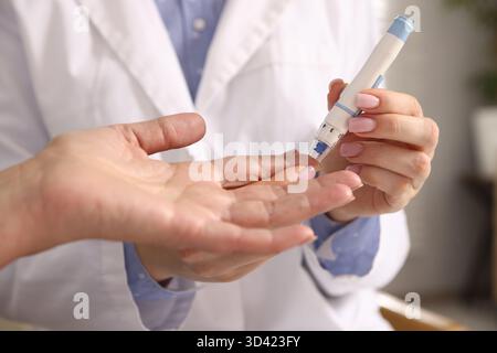 Diabetes. Arzt überprüft den Blutzuckerspiegel des Patienten mit Lanzettenstift drinnen, Nahaufnahme Stockfoto