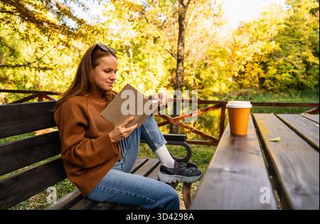 Erwachsene Frau liest ein Buch im Stadtpark, genießt Wochenendfreizeit und digitalen Detox-Lifestyle Stockfoto