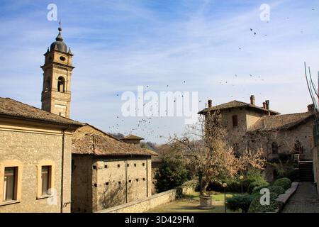Castellarquato, Emilia Romagna, Italien, 03/10/2012 Beschreibung: Historischer Turm und mittelalterliche Steinbauten mit Vogelschar, Castellarquato, Italien Stockfoto