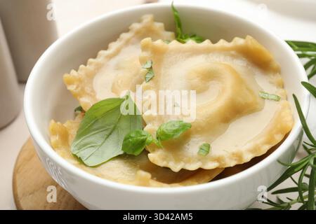 Köstliche Ravioli mit Basilikum in einer Schüssel auf dem Tisch, Nahaufnahme Stockfoto
