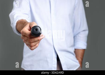 Mann mit versteckter Spionageskamera auf grauem Hintergrund, Nahaufnahme Stockfoto