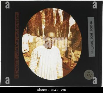 Dieser Glasdiapositiv von ca. 1924-1932 zeigt Cook Matha, der für den Fotografen posiert. Das Bild fängt einen Moment aus dem frühen 20. Jahrhundert ein und zeigt traditionelle Kleidung und den Stil der Zeit. Stockfoto