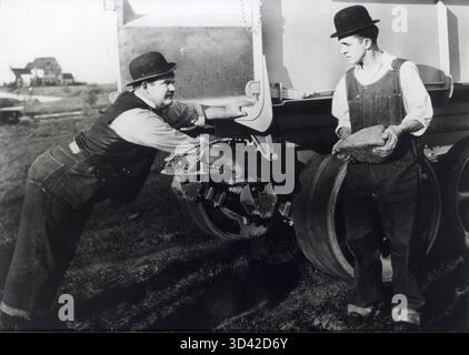 1928 spielen Stan Laurel und Oliver Hardy in der Kurzkomödie The Finishing Touch, in der Laurel einen Stein entfernt, der einen Lkw auf einem Hügel blockiert. Stockfoto