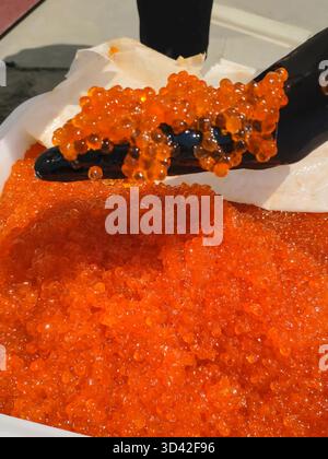 Eier mit einem Handschuher mischen. Roter Kaviar in einem Plastikbehälter. Lachskaviar, Diätkost. Stockfoto