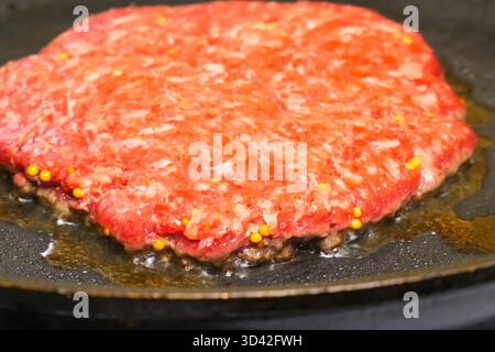 Rohes Schnitzel wird in einer Pfanne gebraten. Sandwich-Kotelett. Stockfoto