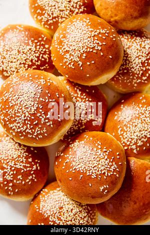 Nahaufnahme frisch gebackener Brioche-Brötchen mit goldener Kruste und Sesamsamen. Weiches und flauschiges hausgemachtes Brot, perfekt für Burger oder Sandwiches. Stockfoto