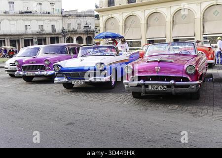 Mehrere farbenfrohe Oldtimer-Cabriolets parken nebeneinander an einer belebten Straße, Havanna, Kuba, Zentralamerika, Großantillen, Karibik, Amerika Stockfoto