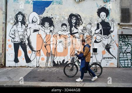 Eine Person spaziert an einem farbenfrohen Wandgemälde mit verschiedenen Charakteren in Montmartre, Paris, Frankreich Stockfoto