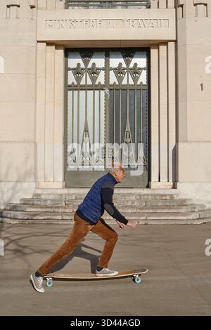 Skateboardmann gleitet an einem sonnigen Tag am Arbeitsministerium in Paris vorbei Stockfoto