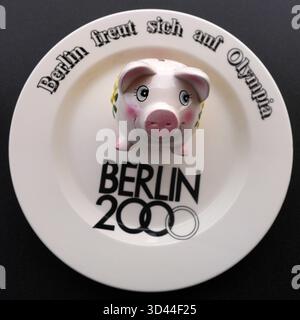 GER, 20251108, Symbolbild, Olympiabewerbung von Berlin, für 2036,2040 und 2044, Symbol mit Sparschwein, mit einem Werbeteller von der Bewerbung aus dem Jahr 2000, Entscheidung fällt im Herbst 2026 *** GER, 20251108, symbolisches Bild, Berlins Olympia-Gebot 2036, 2040 und 2044, Symbol mit Sparschwein, mit Werbetafel aus dem Angebot 2000, Entscheidung wird im Herbst 2026 getroffen Stockfoto