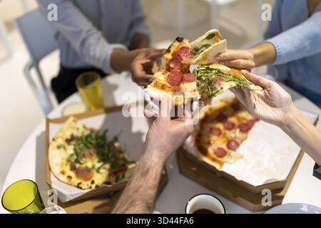 Mittagszeit. Freunde, die sich während des Mittagessens amüsieren und Pizza genießen Stockfoto