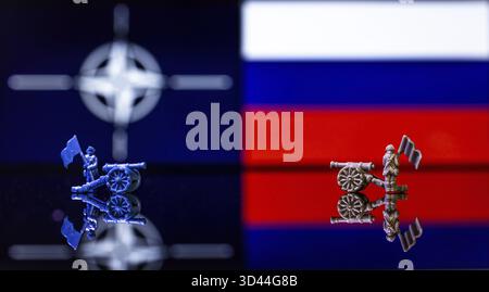 Konzeptuelles Bild des Krieges zwischen Russland und der NATO mit Spielzeugsoldaten und Nationalflaggen auf einem reflektierenden Hintergrund Stockfoto