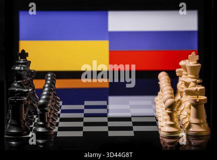 Konzeptuelles Bild des Krieges zwischen Russland und der Ukraine mit Schachfiguren und Nationalflaggen auf einem reflektierenden Hintergrund Stockfoto