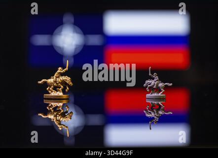 Konzeptuelles Bild des Krieges zwischen Russland und der NATO mit Spielzeugsoldaten und Nationalflaggen auf einem reflektierenden Hintergrund Stockfoto