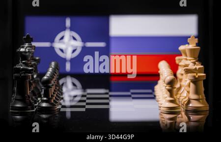 Konzeptuelles Bild des Krieges zwischen Russland und der NATO mit Schachfiguren und Nationalflaggen auf einem reflektierenden Hintergrund Stockfoto
