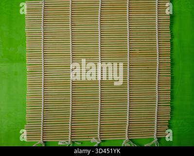 Ansicht von oben auf leere Bambusmatte auf grünem Hintergrund bereit für Sushi Rolling, japanische Küche Vorbereitung Foto für Küchen- und Kochkünstler. Hohe qu Stockfoto