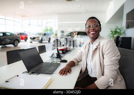Afroamerikanische Geschäftsfrau lächelt an der Rezeption des Autohauses Stockfoto