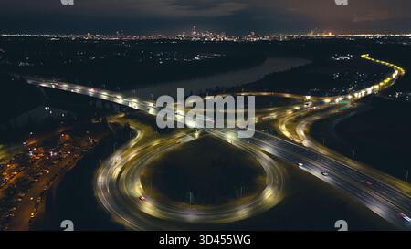 Nächtliche Luftbelichtung kurviger Autobahnen und Überführungen, die von Straßenlaternen erleuchtet werden. Stockfoto