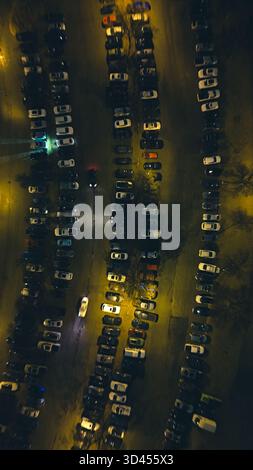 Von oben nach unten geparkte Autos bei Nacht, beleuchtet durch Straßenlaternen. Stockfoto