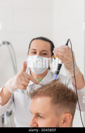 Alopezie. Der Haarausfall des Mannes verbessert die Regeneration der Wachstumsbehandlung, Dermapen-Mikroneedling, Vitamin-Exosomen-Plasmainjektionen. Trichologe Kosmetologe Arzt KopfKopfKopfhautverfahren fraktionelle Mesotherapie Stockfoto