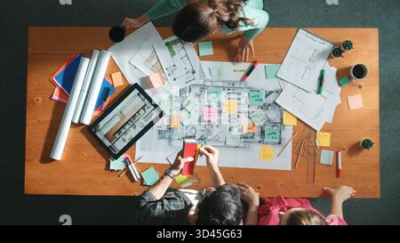 Draufsicht des Ingenieurs, der gemeinsam an der Konstruktion von Gebäuden arbeitet, während er am Besprechungstisch steht, mit Blueprint und Notizen. Draufsicht auf den Innenraum Stockfoto