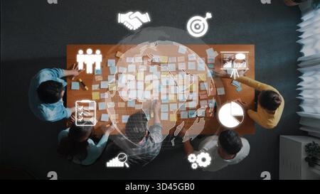 Eine vielfältige Gruppe von Personen nimmt an einer gemeinsamen Strategiesitzung Teil. Sie analysieren Daten und Brainstorming auf einem Holztisch, der mit Sticky bedeckt ist Stockfoto