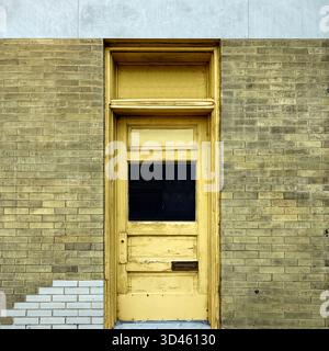 Verwitterter gelber Eingang aus hellem Backstein, der Patina und Geschichte in Chicagos architektonischer Textur und urbanem Charakter vereint Stockfoto
