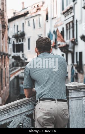 Man leaning on bridge overlooking canal in historic city Stockfoto