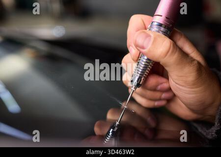 Der Glasreparaturprozess, eine detaillierte Aufnahme von Harzfüllungsfehlern an der Windschutzscheibe, konzentriert sich auf die sorgfältige Reparatur von sternförmigen Spänen an der Windschutzscheibe des Autos Stockfoto