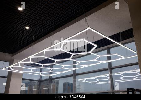 Schlanke sechseckige Leuchten für moderne Büro- und Einzelhandelsumgebungen, innovative Deckenbeleuchtung mit geometrischen Formen, die gewerbliche Akzente setzen Stockfoto
