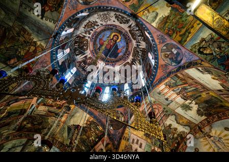 Kunstvolle orthodoxe Fresken und goldener Kronleuchter unter der bemalten Kuppel der Hauptkirche des Bachkowo-Klosters in Bulgarien. Stockfoto