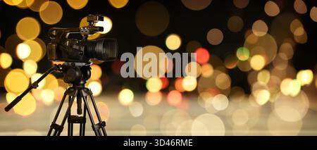 Videokamera auf Stativ gegen unscharfes Licht, Bokeh-Effekt. Bannerdesign Stockfoto