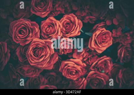 Eine atemberaubende Vintage-Präsentation mit satten roten künstlichen Rosen, perfekt für eine romantische Feier oder einen eleganten Hintergrund. Stockfoto
