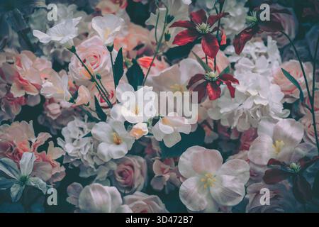 Eine wunderschöne Vintage-Ausstellung mit künstlichen Blumen in verschiedenen sanften Tönen, die eine festliche Kulisse für eine Feier schaffen. Stockfoto