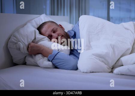 Wunderschöner Blonder Mann, Der Friedlich Auf Dem Weißen Hotelkissen Schläft Stockfoto