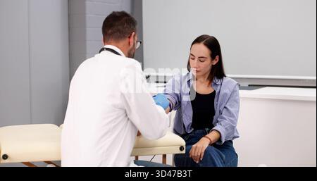 Gesundheitscheck: Weibliche Ärztin Nimmt Blutprobe Vom Lächelnden Mann Stockfoto