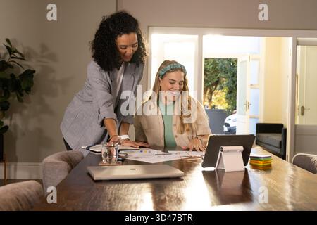 Zusammenarbeit mit verschiedenen weiblichen Kollegen, die Karten am Bürotisch überprüfen, mit Laptop und Notizen Stockfoto