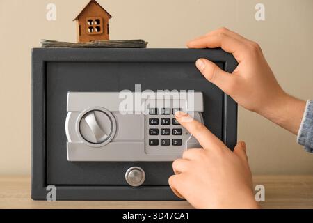 Mann öffnet den Safe in einem Regal neben der beigefarbenen Wand, Nahaufnahme Stockfoto
