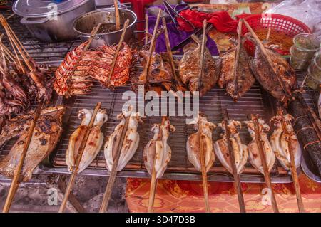 Verschiedene Barbecue-Tintenfische, Garnelen und Fisch auf dem Grill an einem Marktstand unter freiem Himmel. Der Krabbenmarkt. Kep, Kambodscha. © Kraig Lieb Stockfoto