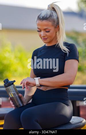 Frau in sportlicher Kleidung, die Smartwatch während des Workouts im Freien verwendet Stockfoto