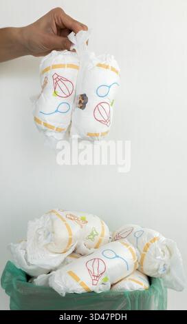 Die Hand wirft gebrauchte Windeln in den vollen Papierkorb. Stockfoto