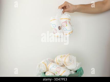 Die Hand wirft gebrauchte Windeln in den vollen Papierkorb. Stockfoto