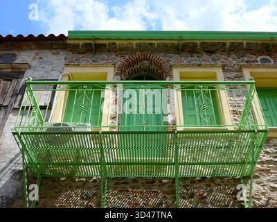 Ein grüner Balkon und Fensterläden an der Fassade eines restaurierten alten Gebäudes auf der Insel Lesbos, Griechenland Stockfoto